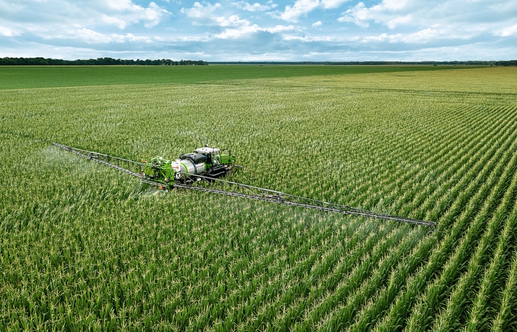 Fendt Rogator 900 beim spritzen von einem Maisfeld von hinten