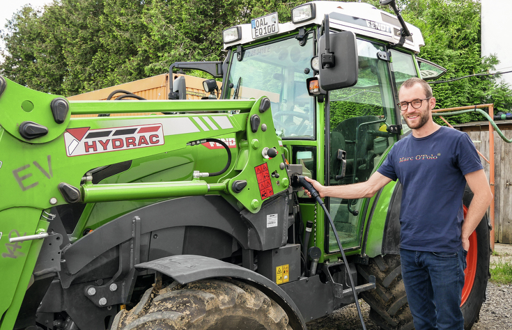 Landwirt lädt den stehenden batteriebetriebenen Fendt e100 Vario mit Frontlader