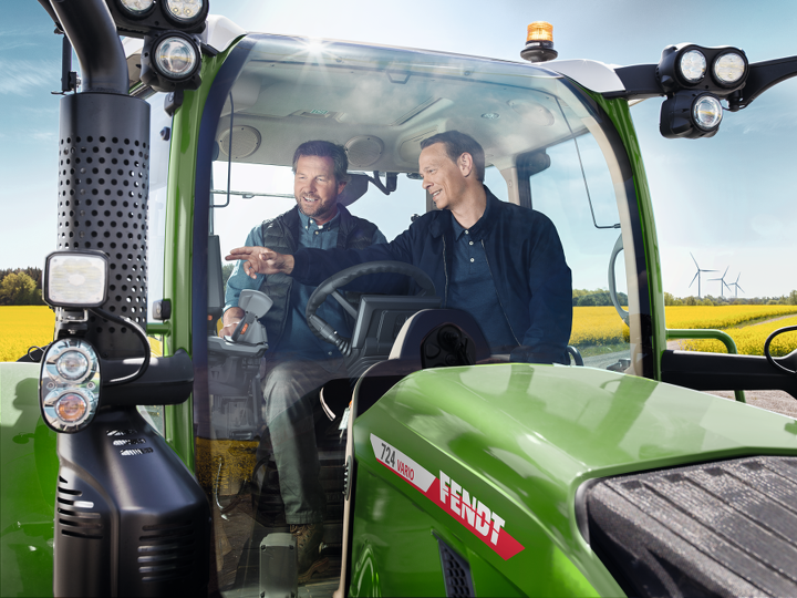 Ein Landwirt sitzt mit einem Fendt Händler auf einem Traktor und lässt sich die Maschine erklären