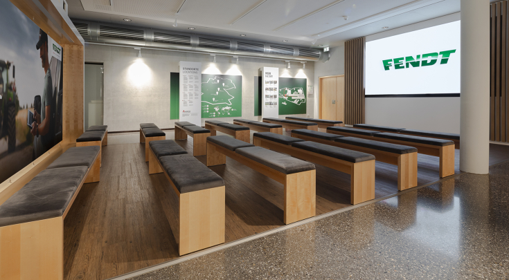 LED-Wand mit Fendt Logo vor Holzbänken