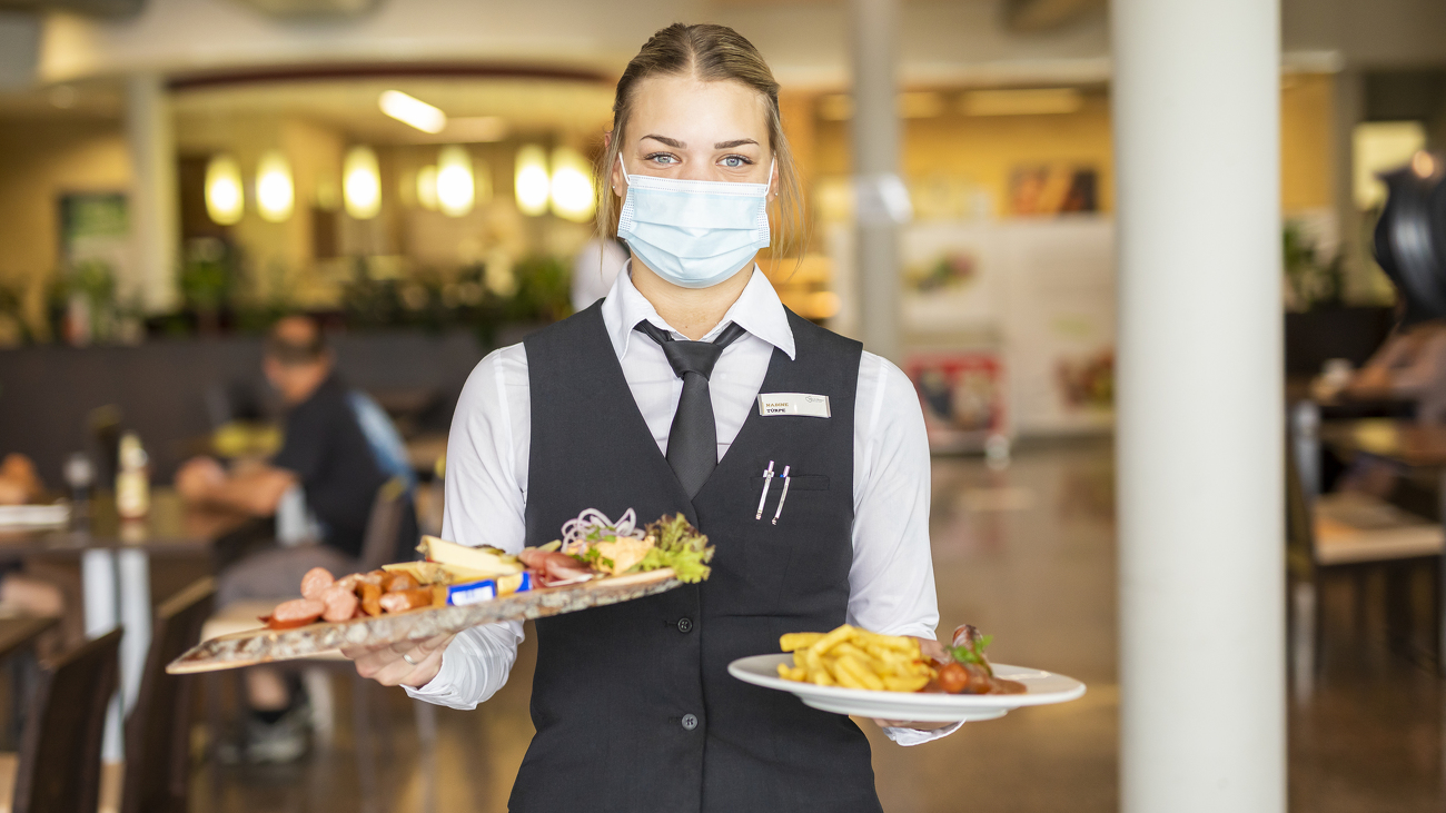 Innenansicht des Fendt Dieselross Restaurants, eine Bedienung serviert das Essen.