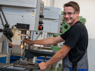 Der Auszubildende Industriemechaniker bedient eine Maschine in der Lehrwerkstatt