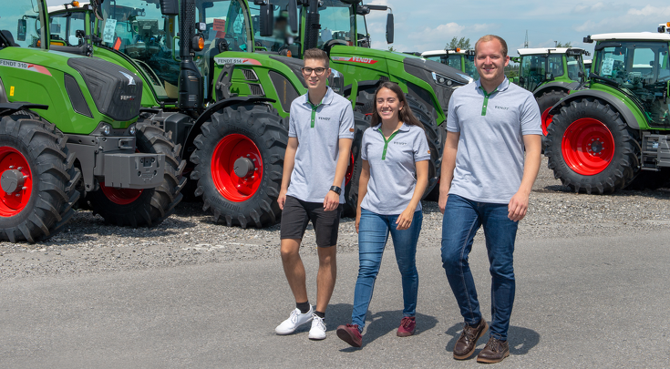 3 Auszubildende laufen auf die Kamera zu, im Hintergrund sind Fendt Traktoren zu sehen