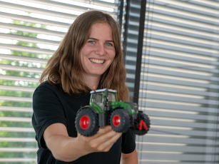 Die Auszubildende Technische Produktdesignerin hält einen Fendt Modellschlepper in der Hand