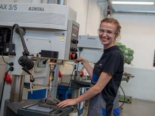 Die Auszubildende Industriemechanikerin bedient eine Maschine in der Lehrwerkstatt