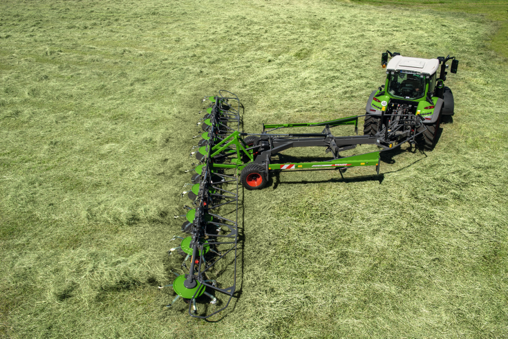 Ein grüner Fendt Traktor mit roten Felgen und ein grüner Fendt Lotus 1020 T & 1250 T in der Vogelperspektive während dem Wenden auf einem grünen Feld.