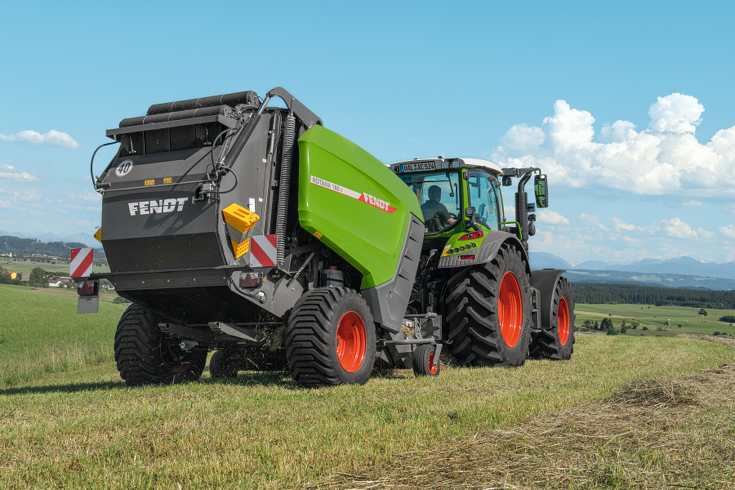 Fendt Rotana 180 V auf der Wiese Fendt Rotana 180 V auf der Wiese. Im Hintergrund sind Berge und blauer Himmel mit Wolken zu sehen.