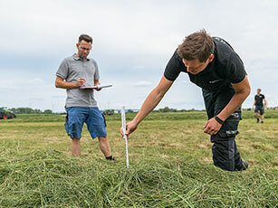 Zwei Männer stehen auf einem Feld und vermessen die Testschwaden
