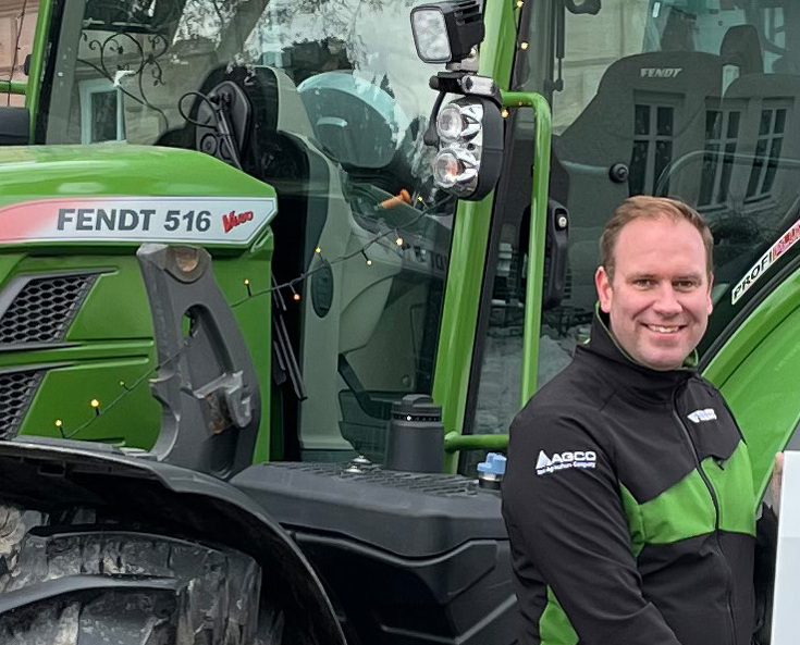 Ein Mann steht vor einem Fendt Traktor und lächelt