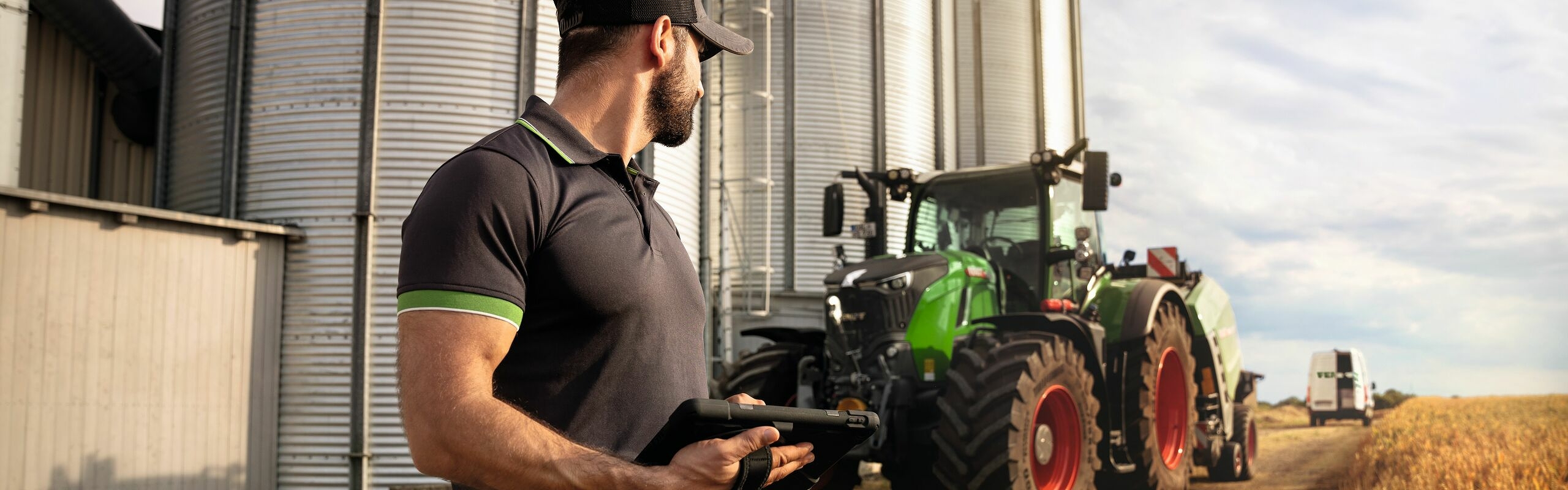 Ein Fendt Service-Techniker schaut auf einen Fendt Traktor 700 Vario Gen6 am Feldrand