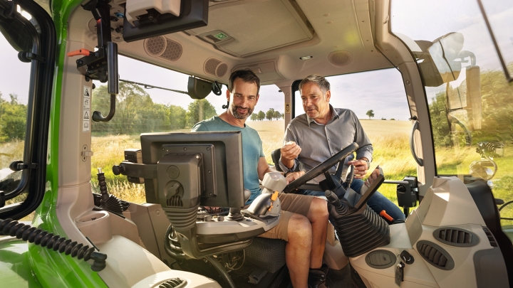 Ein Fendt Händler in der Kabine eines grünenTraktor-Vorführmodells Fendt 700 Vario Gen7 beim Landwirtskunden auf dem Gelände