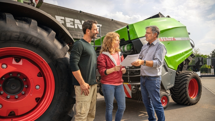 Ein Fendt Händler auf seinem Firmengelände mit einem Landwirtsehepaar im Vertriebsgespräch