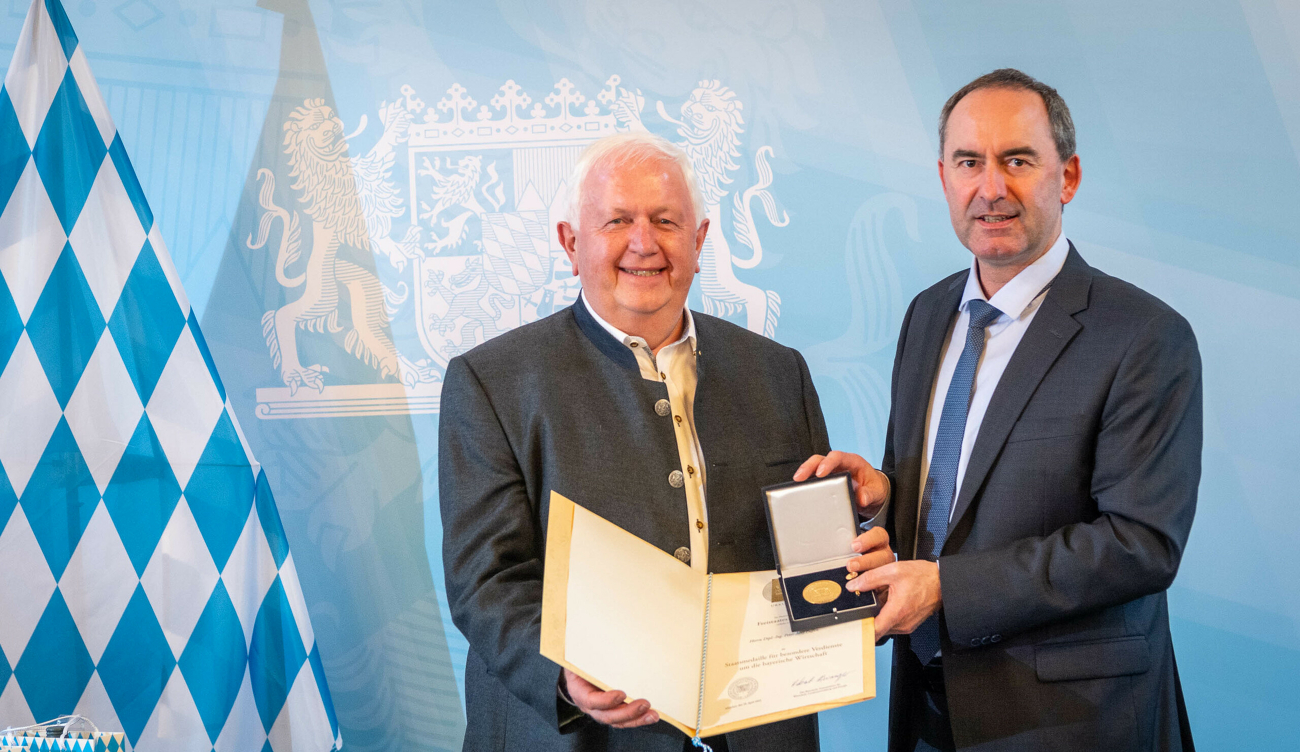 Peter-Josef Paffen erhält die Bayerische Staatsmedaille von Hubert Aiwanger (Bayerischer Staatsminister für Wirtschaft, Landesentwicklung und Energie) im Hintergrund eine bayerische Flagge