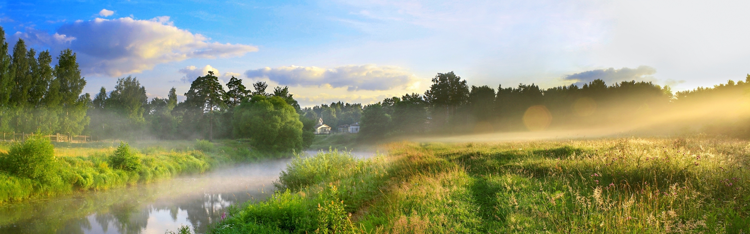 Panoramablick auf eine neblige Flusslandschaft bei Sonnenuntergang mit einem kleinen Haus im Hintergrund