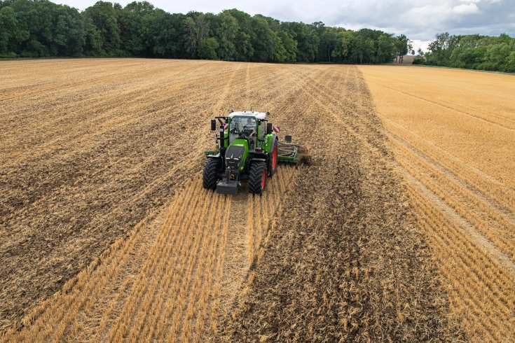 Ein Fendt Traktor mit einer Scheibenegge fährt über ein Stoppelfeld