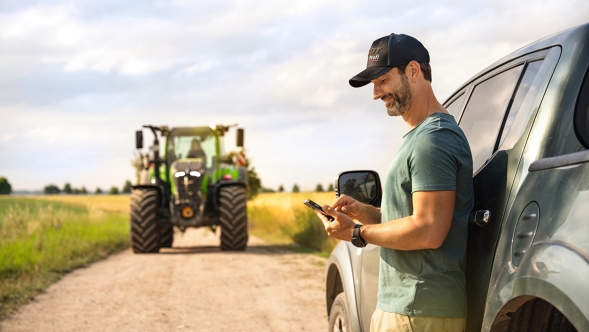 Ein Landwirt schaut auf seinem Handy in seiner MY AGCO App nach Neuigkeiten
