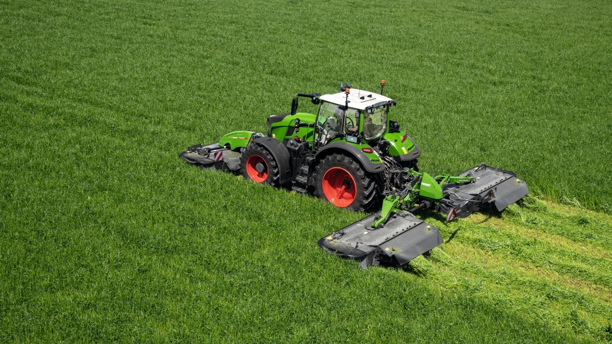 Ein grüner Fendt Traktor mit Slicer 860 KC mäht Gras