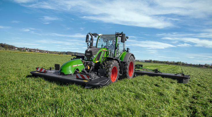 Ein grüner Fendt Traktor mit Fendt Slicer Mähwerk im Feld