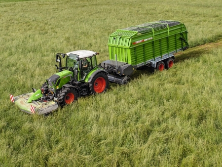 Fendt 300 Vario Traktor mit Fendt Frontmähwerk und Fendt Ladewagen beim Mähen und Grassammeln auf einer Wiese