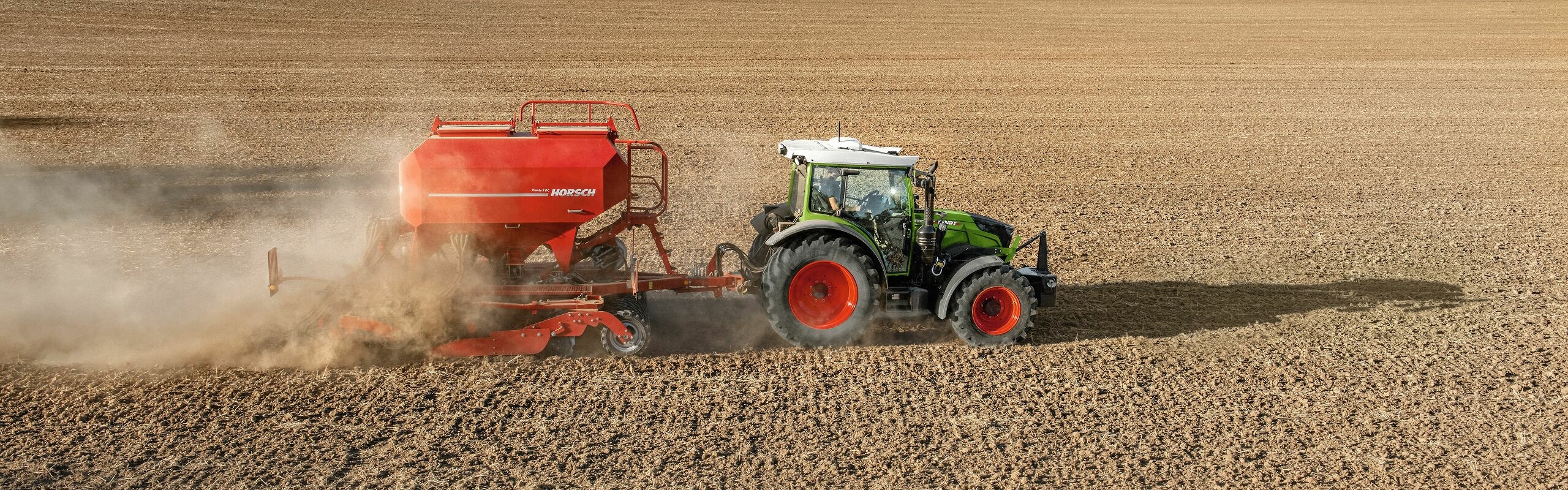 Grüner Fendt 200 Vario mit roter Horsch Sähmaschine auf dem Feld