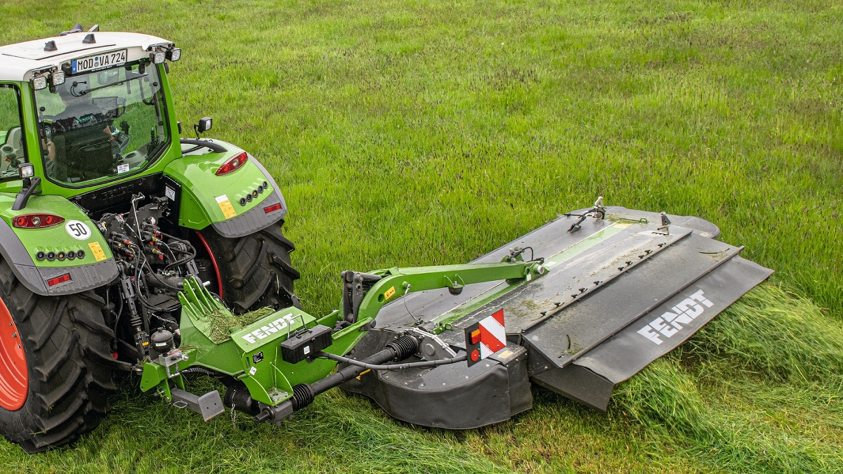 Nahaufnahme eines Fendt Slicer Heckmähwerks beim Mähen eine grünen Wiese.