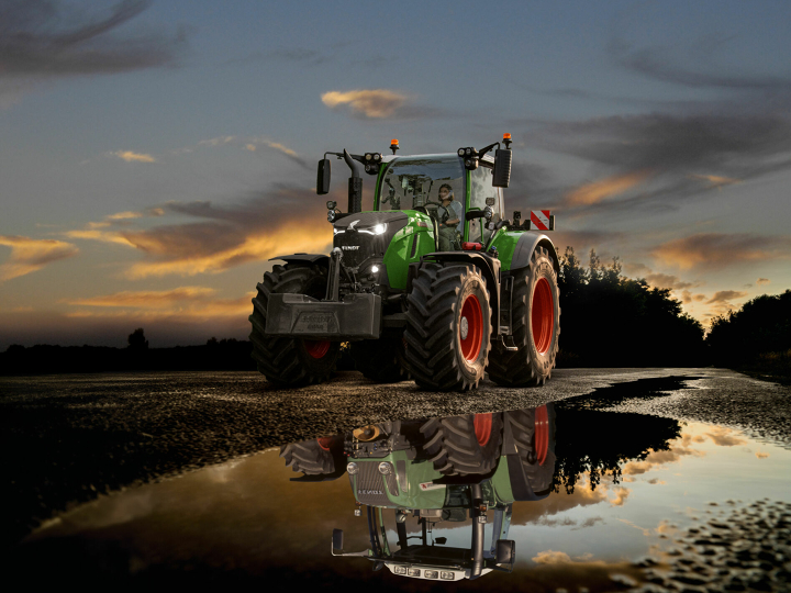 7 Generationen Fendt 700 Vario Ein Fendt 700 Vario Gen7 auf der Straße vor dramatischem Sonnenuntergangshimmel
