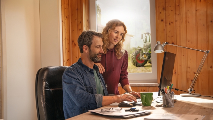 Ein Landwirtsehepaar prüft am PC seinen automatisierten Datenaustausch per Fendt Smart Farming Agronomie
