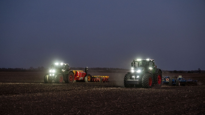 Der Fendt 1000 Vario und der Fendt 800 Vario arbeiten bei Dunkelheit mit eingeschaltetem Scheinwerfer gemeinsam auf einem Feld.