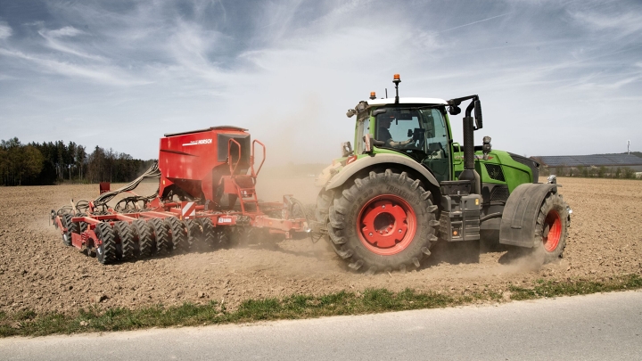 Ein Fendt 700 Vario mit Ladewagen fährt im Sommer auf einer Landstraße