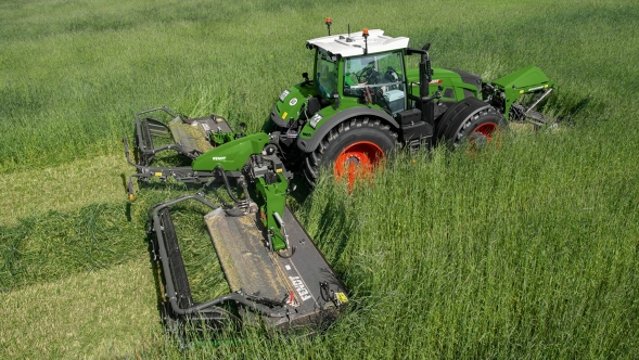 Fendt Slicer Ein Landwirt mäht mit einem Fendt Traktor und einem Fendt Slicer Front- und Heckmähwerk eine hohe grüne Wiese.