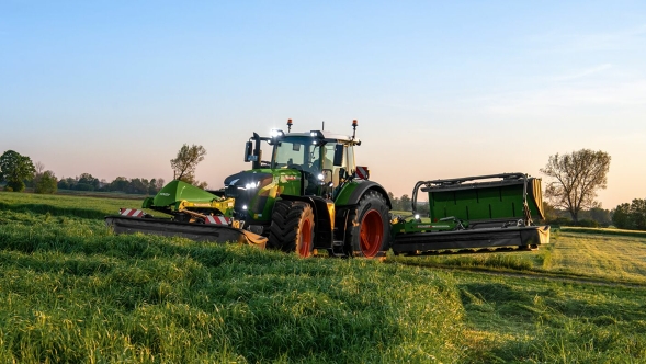 Fendt Slicer Front- und Heckmähwerk Ein Landwirt fährt bei leichter Dämmerung mit einem Fendt Slicer Front- und Heckmähwerk auf einer grünen Wiese.