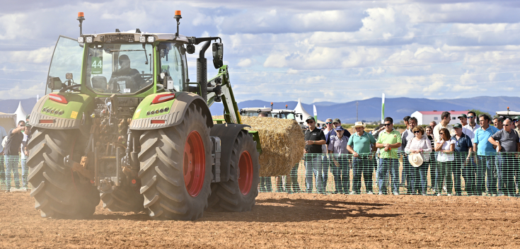 Ein Fendt Traktorelädt Stroh bei einer Fendtgüinos Vorführung Ein Fendt Traktorlädt einen Strohballen mit dem Frontlader bei einer Fendtgüinos Vorführung im Hintergrund Zuschauer