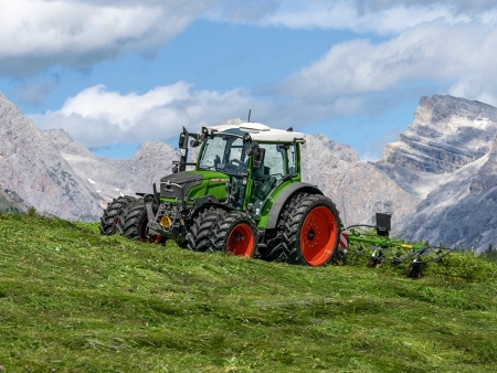 Ein grün lackierter Fendt 200 Vario mit roten Felgen bei der Grünfutterernte im alpinen Hochgebirgsraum