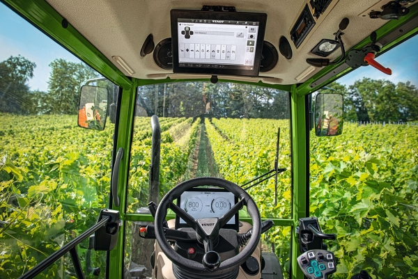 Fendt 200 V/F/P Vario in den Weinbergen Man sieht die Sicht aus der Kabine des Fendt 200 V/F/P Vario, der durch die Weinberge fährt. In der Kabine befindet sich das Lenkrad und das Terminal im Dach der Kabine.