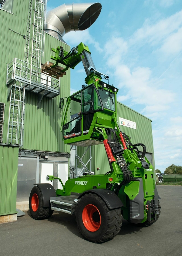 Teleskoparm des Fendt Cargo T955 Fendt Cargo T955 mit hochgefahrener Kabineund ausgefahrenem Teleskoparm vor einer Lagerhalle
