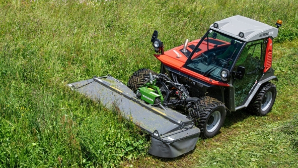 Ein grüner Fendt Slicer Alpin mäht eine grüne Wiese und hinterlässt eine Spur frisch geschnittenen Grases.