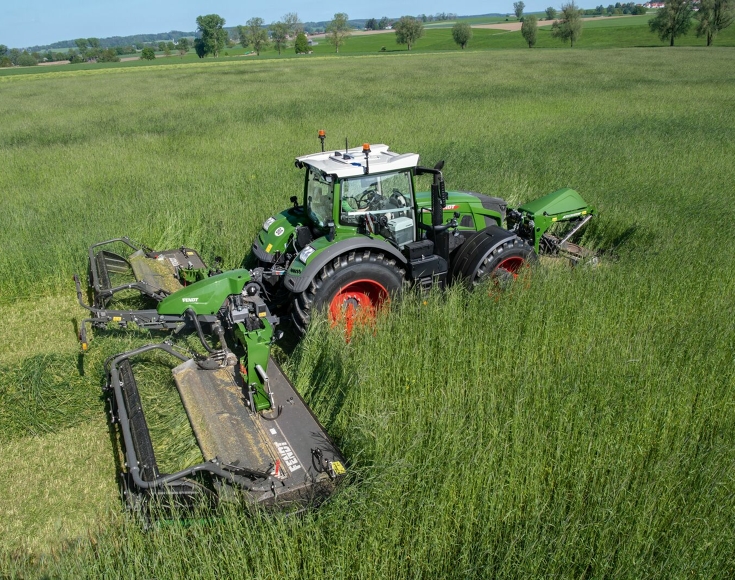 Fendt Slicer 960 KCB Pro Ein Fendt Traktor fährt mit der Mähwerkskombination Fendt Slicer 960 KCB Pro durch hoch stehendes Gras im Grünland und mäht