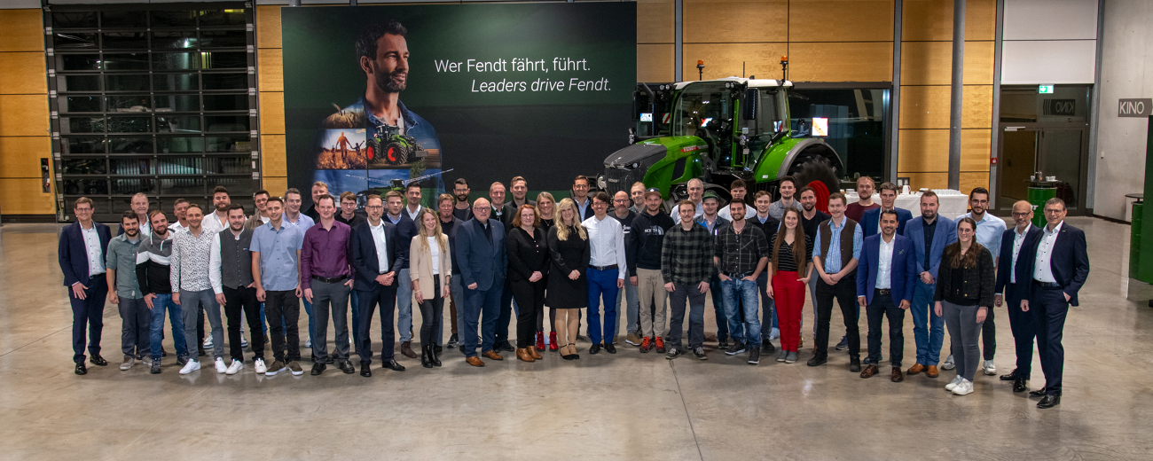 Fendt Mitarbeitende mit 10 Jahren Betriebszugehörigkeit gemeinsam mit der Fendt Geschäftsführung vor einem Fendt Traktor