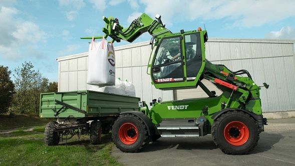 Ausgefahrener Fendt Cargo T955 Der ausgefahrene Fendt Cargo T955 belädt vor einer Lagerhalle einen Ladewagen.