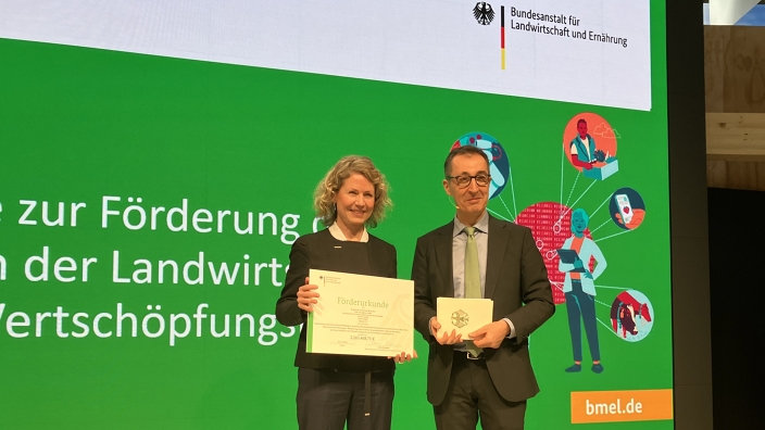 Manja Morawitz erhält den Förderbescheid von Cem Özdemir auf einer Bühne