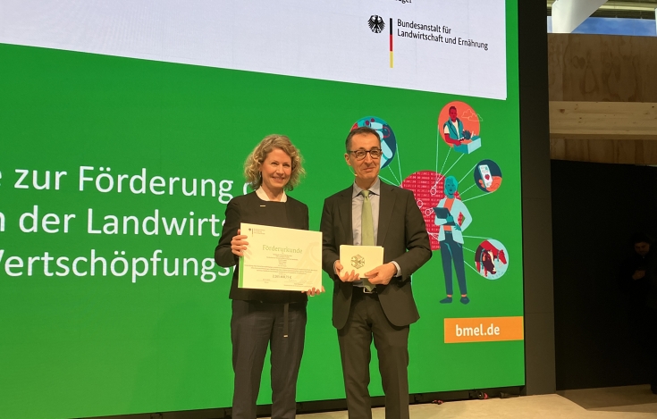 Manja Morawitz erhält den Förderbescheid von Cem Özdemir auf einer Bühne