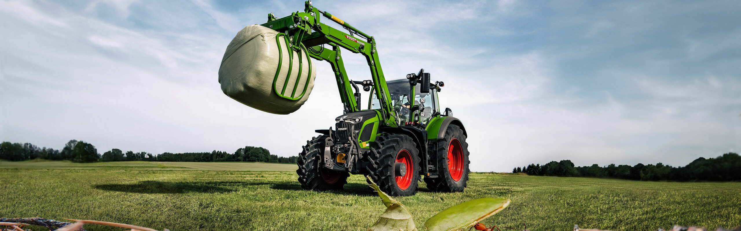 Fendt 600 Vario mit Frontlader auf einem Feld mit Ameisen im Vordergrund