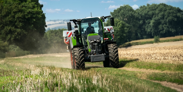 Fendt mit Düngerstreuer auf Feldweg