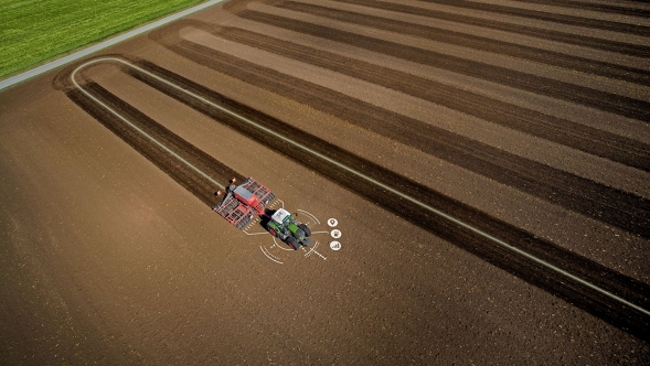 Ein Traktor fährt über einen Acker, dabei ist die präzise Spurführungslinie zu sehen.