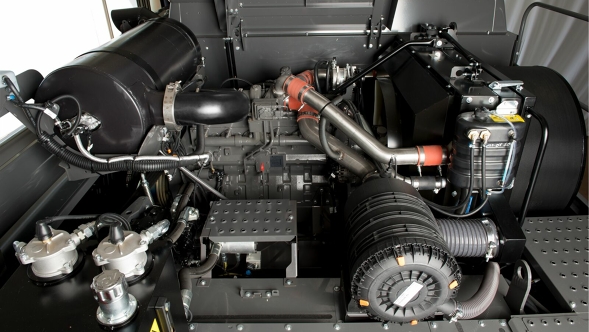 Der geöffnete Motorraum zeigt verschiedene mechanische Komponenten wie Rohre, Schläuche und Metallstrukturen.