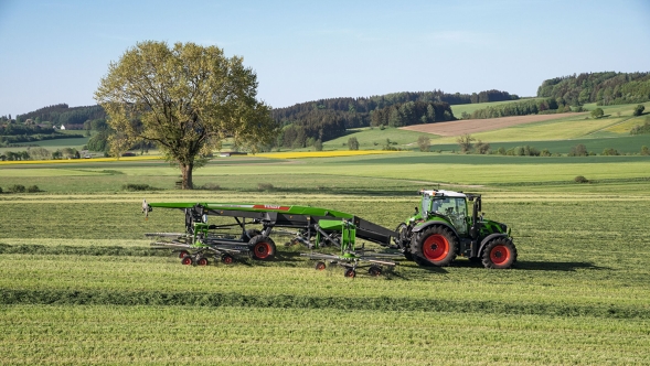 Fendt Former 14055 PRO Ein grüner Fendt Traktor mit roten Felgen und angehängtem Fendt Former 14055 PRO beim Schwadeinsatz auf einem grünen Sommerfeld