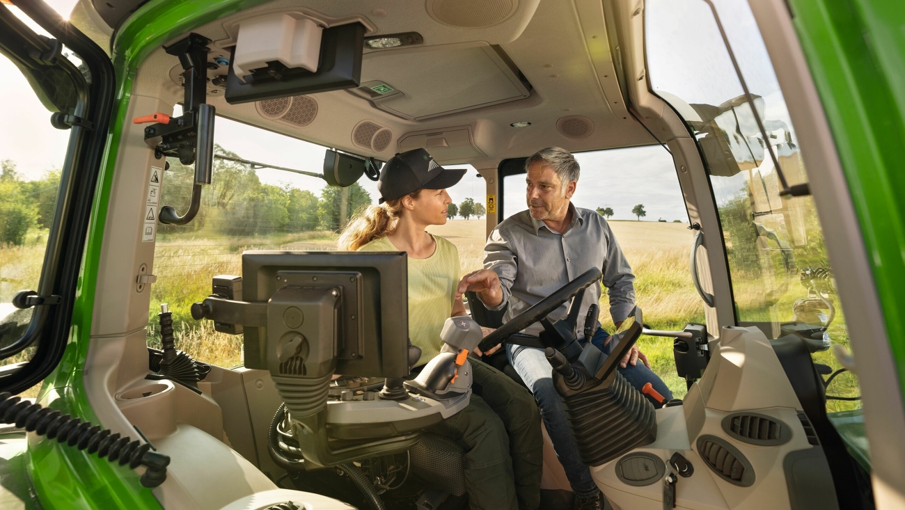 Ein Fendt Händler in der Kabine eines grünenTraktor-Vorführmodells Fendt 700 Vario Gen7 bei der Landwirtskundin auf dem Gelände