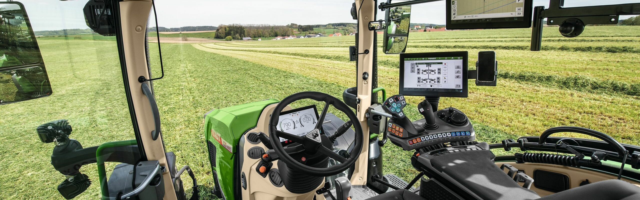 Innenansicht der Kabine des Fendt 600 Vario mit Aussicht auf eine grüne Wiese.
