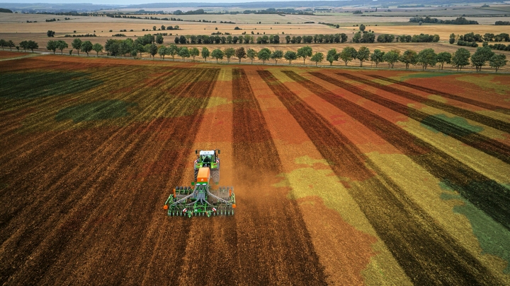Ein grüner Fendt Traktor mit Anbaugerät bei der präzisen Bodenbearbeitung dank FendtONE Maschinensteuerung