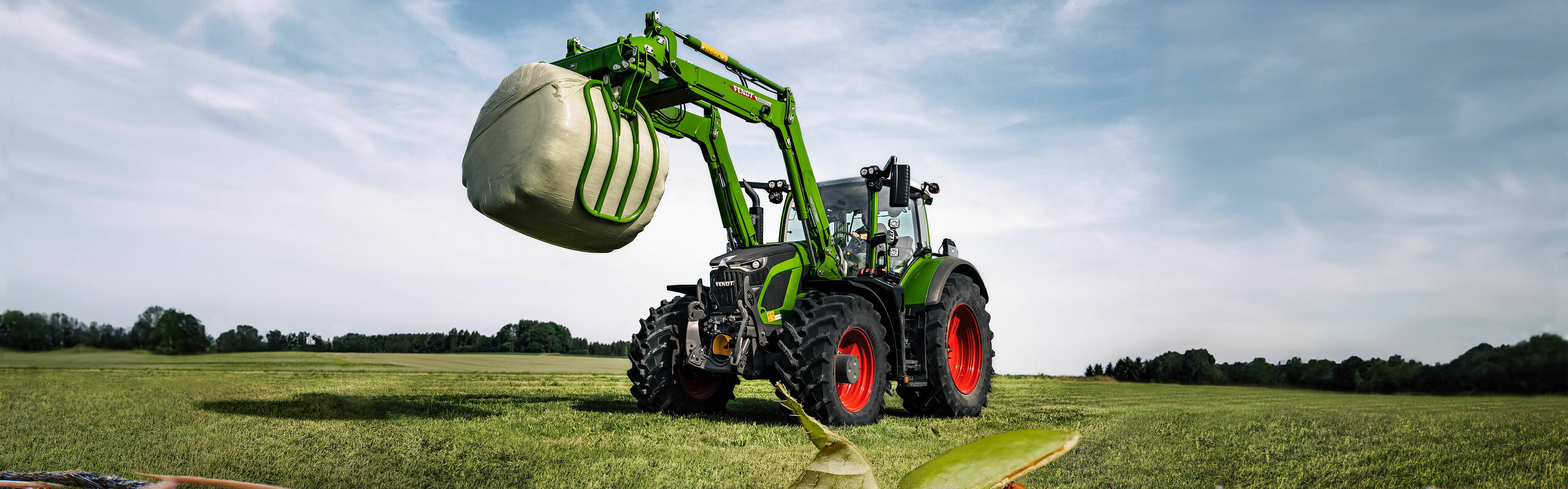 Fendt 600 Vario mit Frontlader auf einem Feld mit Ameisen im Vordergrund